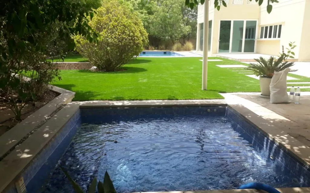 Small concrete villa pool with dark mosaic tiles and water jets in Dubai