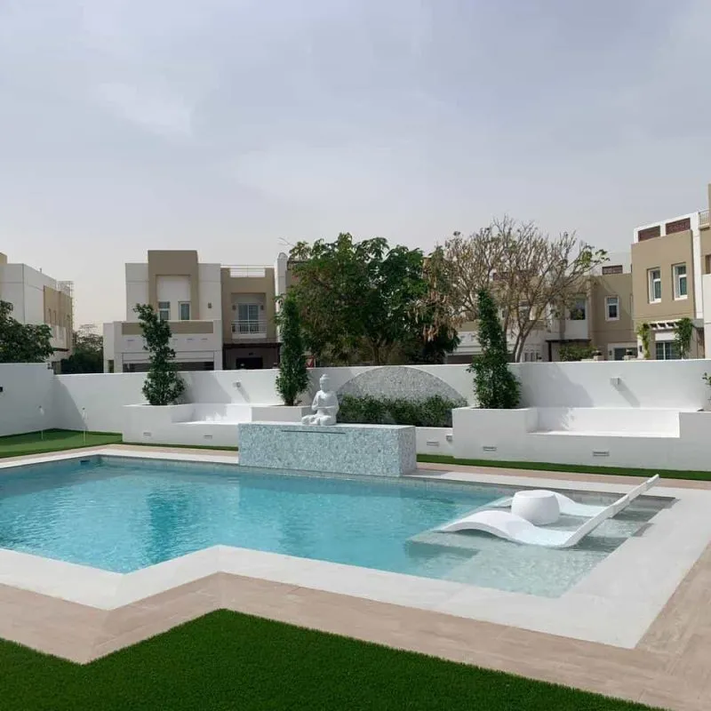 Modern villa pool with tanning ledge and white boundary walls in Dubai