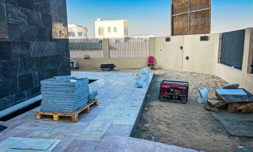 Natural stone floor tiling and decking installation work in villa backyard with materials and generator - flooring installation Dubai