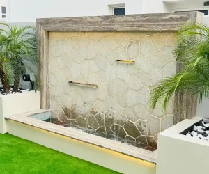 Luxury outdoor water feature wall with stone cladding and garden illumination designed by MasterMaint Dubai.