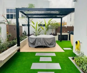 Custom black aluminum pergola and outdoor shading structure with lounge seating in a Dubai backyard landscape.
